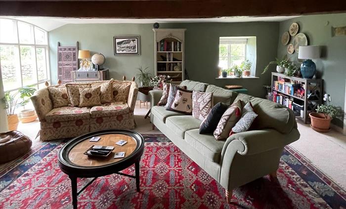 The snug at ysgubor degwm seadog and stone is a lounge with green hues and a cosy feel.